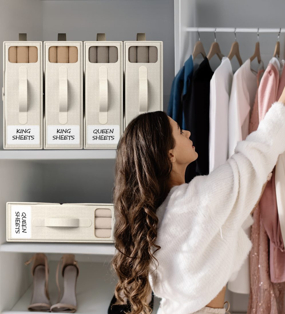 Beige bed sheet organizers on a closet shelf beside hanging clothes